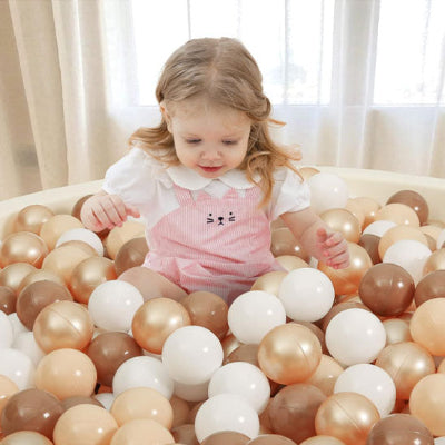 Bébé exerce sa motricite en saisissant, pressant et relachant balle piscine a balle.