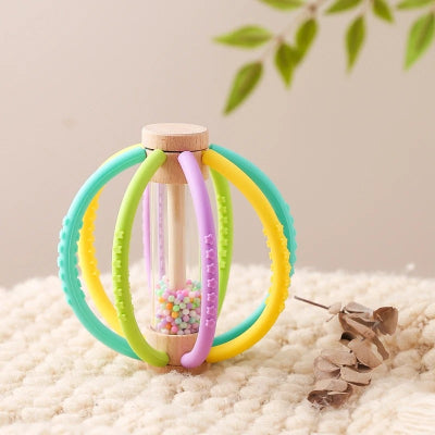 Baton de pluie bébé fait de bois et de silicone alimentaire, agencer des déclinaisons des couleurs verte, jaune et violet.