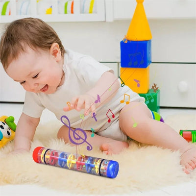 Bébé émerveillé par la musique que libère le baton de pluie en roulant, tend la main pour l'atteindre.