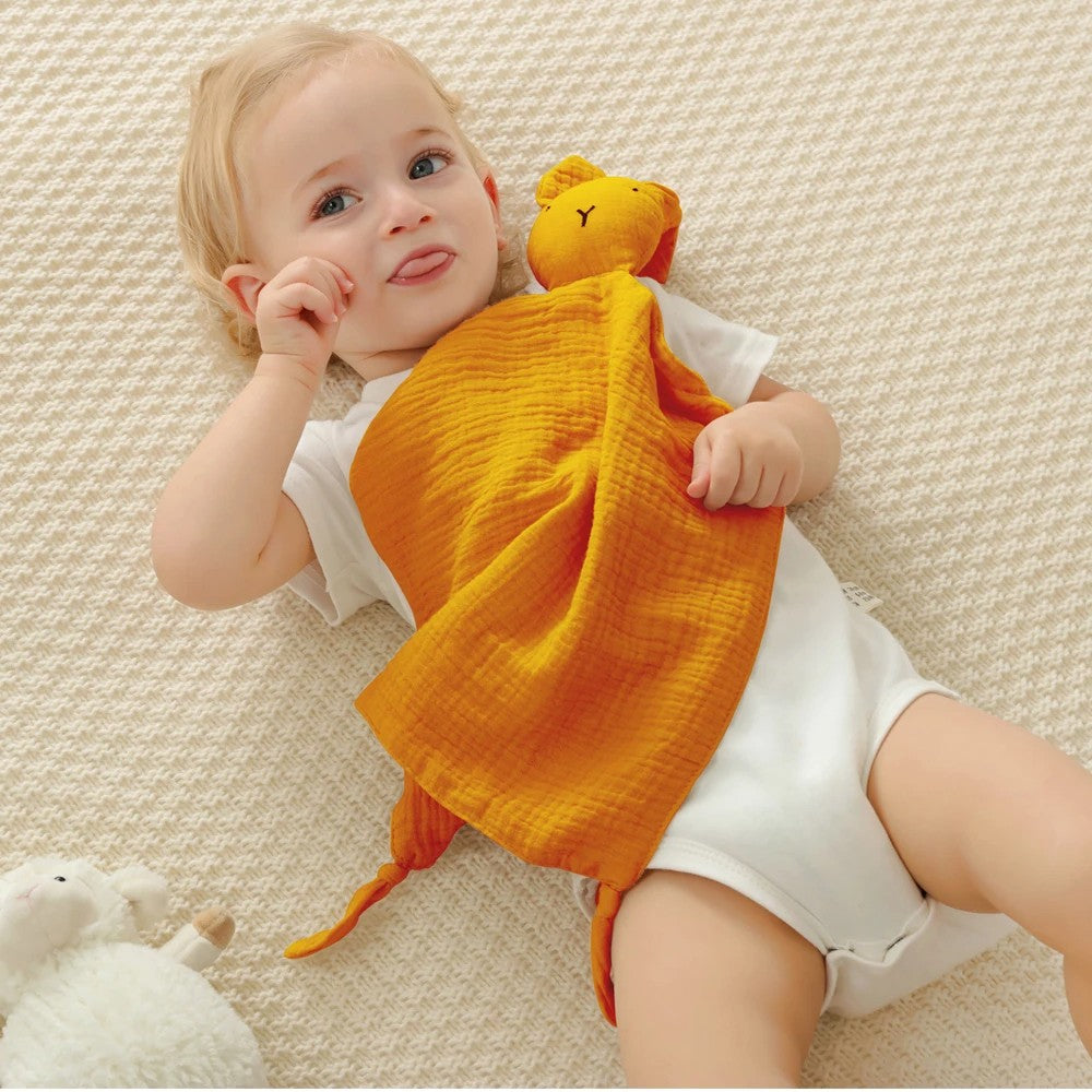 Un bébé joyeux et taquin avec son doudou lapin.