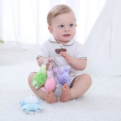 Bébé qui frissonne en caressant ses hochets des bouts de doigts