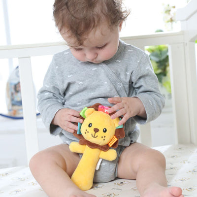 Bébé explore son hochet de tous ses doigts, regard captivé par ses divers couleurs et étiquettes.